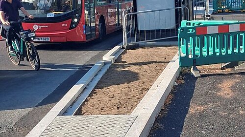A street with a bus stop, bike lane under construction