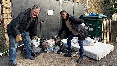 Two people pointing at fly tipped rubbish on a street