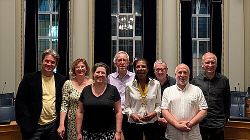 A photo of 8 people in an ornate room