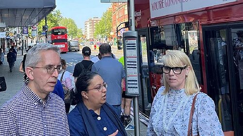 Photo of two men and a woman by a bus stop