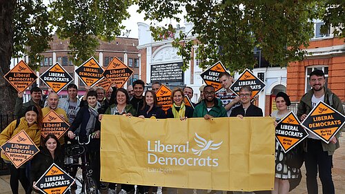 Assembled people holding Lib Dem signs