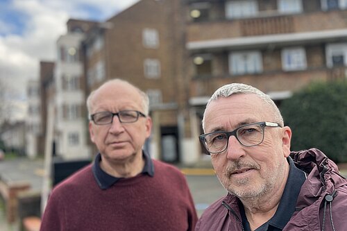 Photo of two men, councillors, in front of a housing block